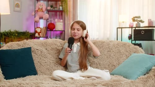 Girl Singing with Microphone on Sofa at Home