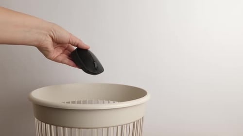 E55 1. A broken computer mouse is thrown into the trash. Disposal of household waste.