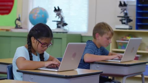 Students Work on Laptop Computers at Desks in School Classroom Child