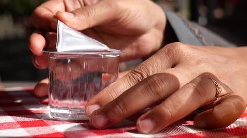 Hands Opening Container of Water on Picnic Table