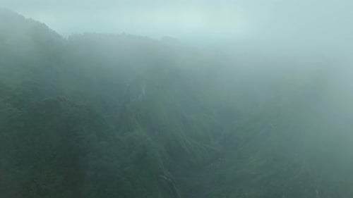 Aerial view of green mountains covered in mist, Indonesia.