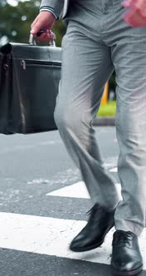 Legs, businessman and walking with briefcase at pedestrian crossing for travel