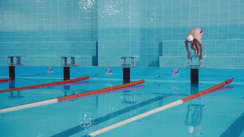 A Young Attractive Athlete Male Swimmer Dives Into the Pool and Swims Underwater for a Long Time