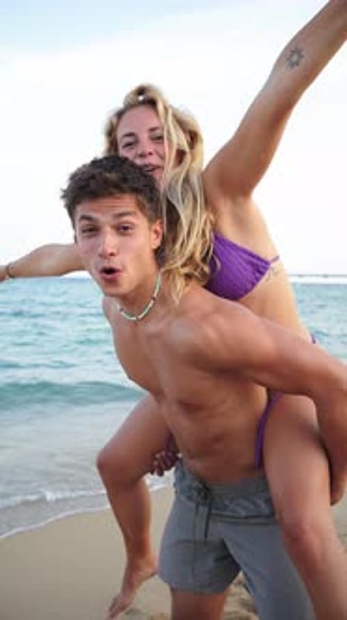 Joyful Young Couple Sharing a Fun and Playful Moment of Happiness By the Serene Beach Coastline