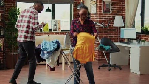 Woman Ironing Clothes in Living Room at Home