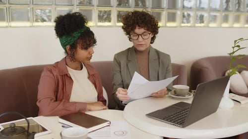 Zwei Mitarbeiterinnen diskutieren Dokumente im Café