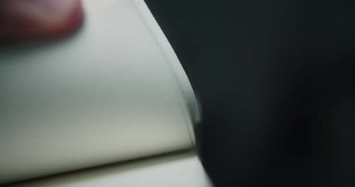 Seiten eines Buches, das schnell durch die Hand eines jungen Mannes mit gedämpfter Beleuchtung geht.