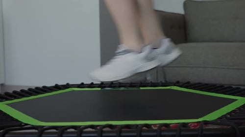Woman Exercising on a Mini Trampoline Indoors