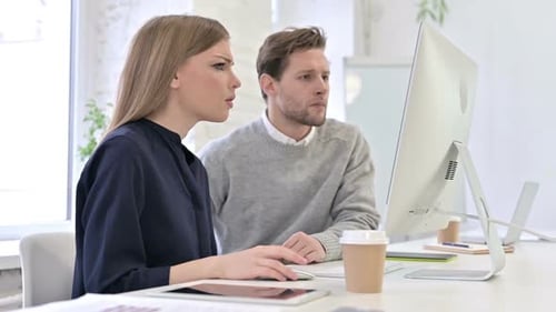 Upset Creative Team Reacting to Failure on Desktop in Office