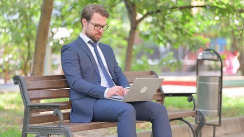 Beard Businessman Working on Laptop while Sitting Outdoor on Bench