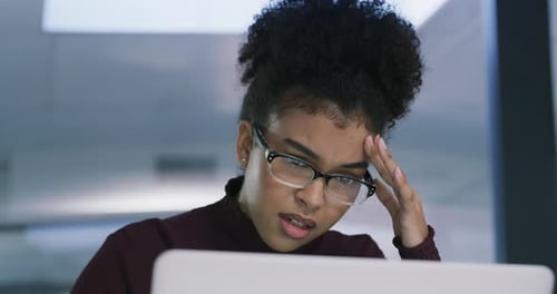 4k video footage of a young businesswoman looking stressed while using a laptop in a modern office