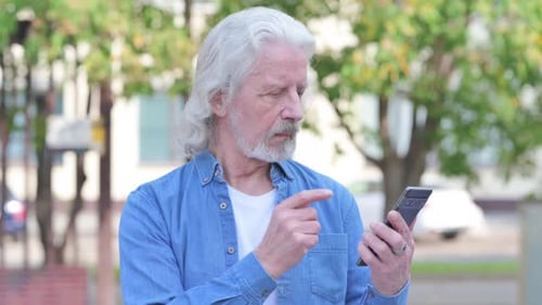 Senior Man Using Smartphone Outdoors in the City