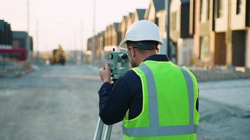 Surveyor Using Theodolite at Construction Site During the Day