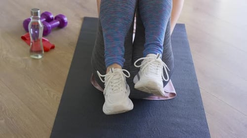 Afroamerikanerin blaue Leggings beim Knirschen mit Handtuch unter den Hüften auf Hausmatte Gebäudekern