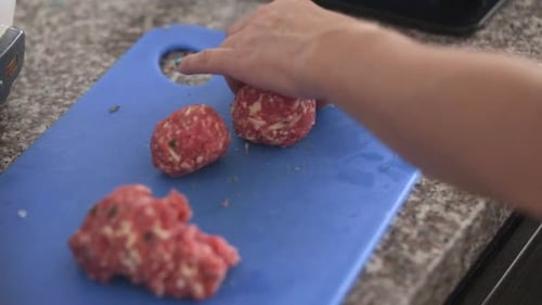 Hand Shapes Meatballs on Blue Cutting Board