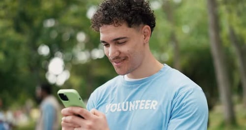 Volunteer Using Mobile Phone in Park with Team