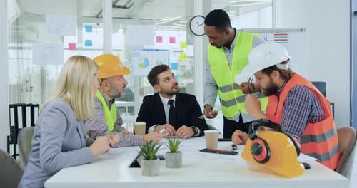 Construction Team Collaborating on Blueprints in Office