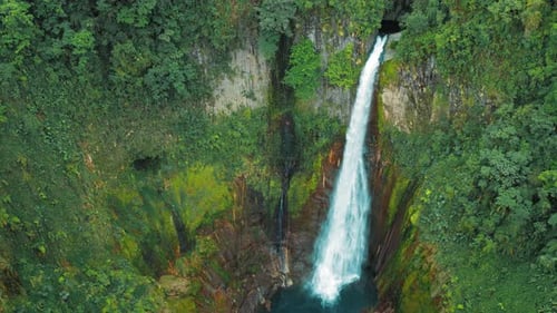 Powerful Waterfall Plunges Into a Turquoise Pool Through Vivid Cliffs in Blue Falls Costa Rica