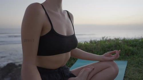 Woman Meditating by Ocean at Sunset