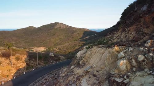 Drohne fliegt über eine malerische Bergstraße mit felsigen Klippen und malerischer Landschaft