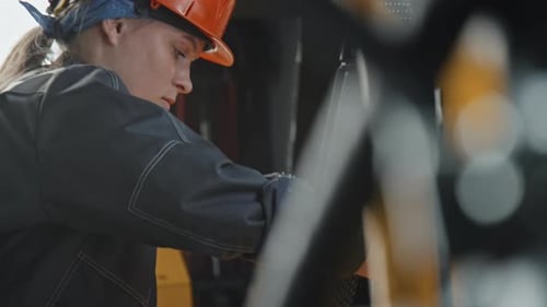 Female Mechanic Fixing Bulldozer Machine at Industrial Plant