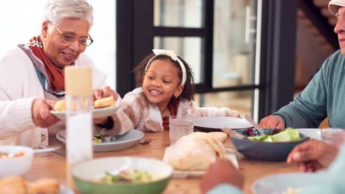 Family Meal with Grandmother Offering Food to Child
