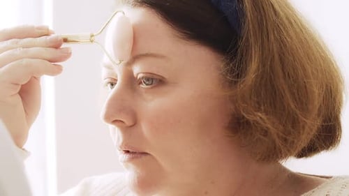 Woman Using Facial Roller at Home