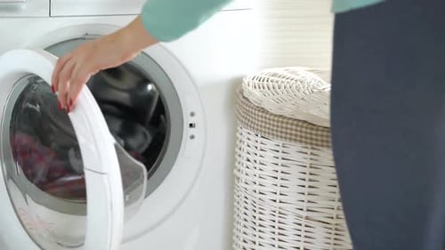 Woman Loading Clothes into Washing Machine at Home