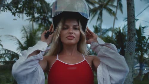 Woman with Blonde Hair Puts on Motorcycle Helmet