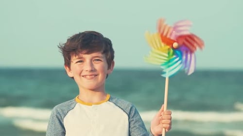 Happy boy spinning pinwheel toy and joyfully smiles