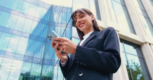 Woman Using Phone Outside Office Building Smiling