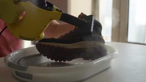 Closeup Side View of Unrecognizable Man Wearing Rubber Gloves Cleaning Dirty Winter Shoes Over Basin