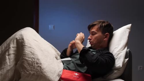 Man blowing his nose in bed with cold