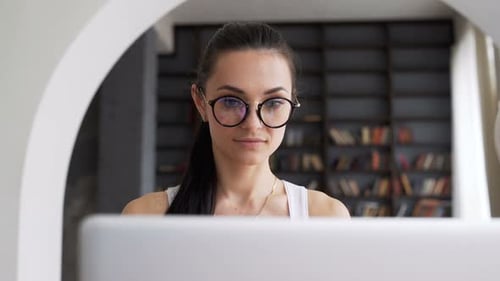 Woman Works at Computer Wearing Glasses in Home