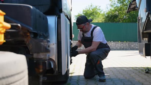 Man Repairing Truck in Urban Workplace on Sunny Day