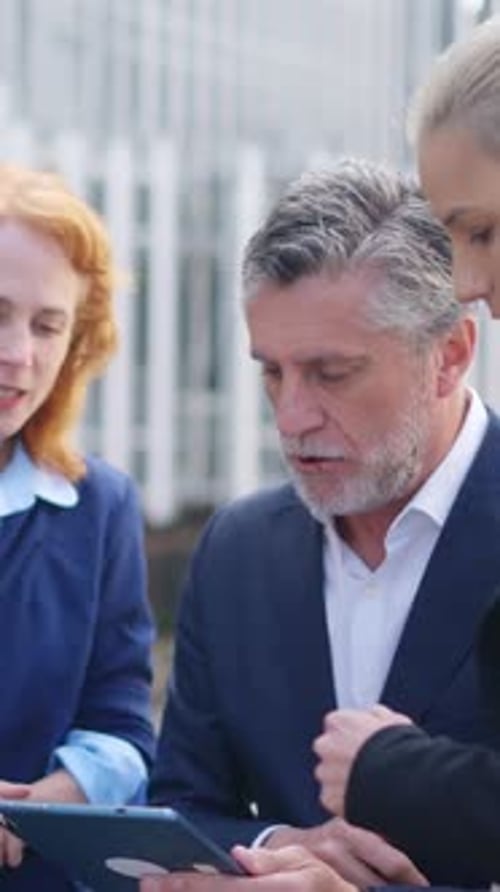 People in Suits Using Tablet Outside