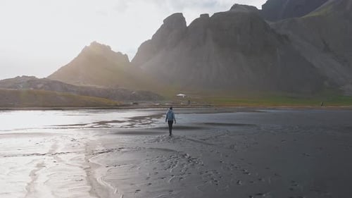 Person Walking on Reflective Black Sand Beach at Stokksnes Iceland