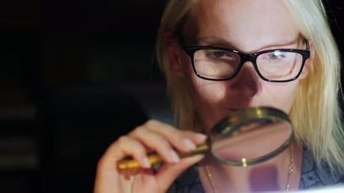 Une femme regarde quelque chose à travers une loupe
