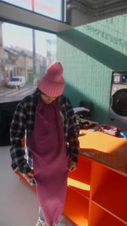 Young Adult Folding Clothes at Bright Urban Laundromat