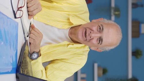 Vertical video of Home office worker old man talking facetime looking at camera.