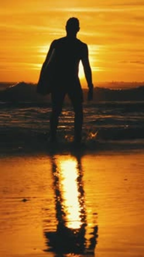Silhouette of Man with Surfboard on Beach at Sunset