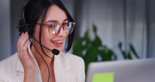 Smiling Woman Uses Headset at Workplace
