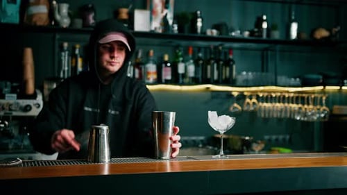 A professional bartender takes a shaker in his hands The process of making cocktails in a club