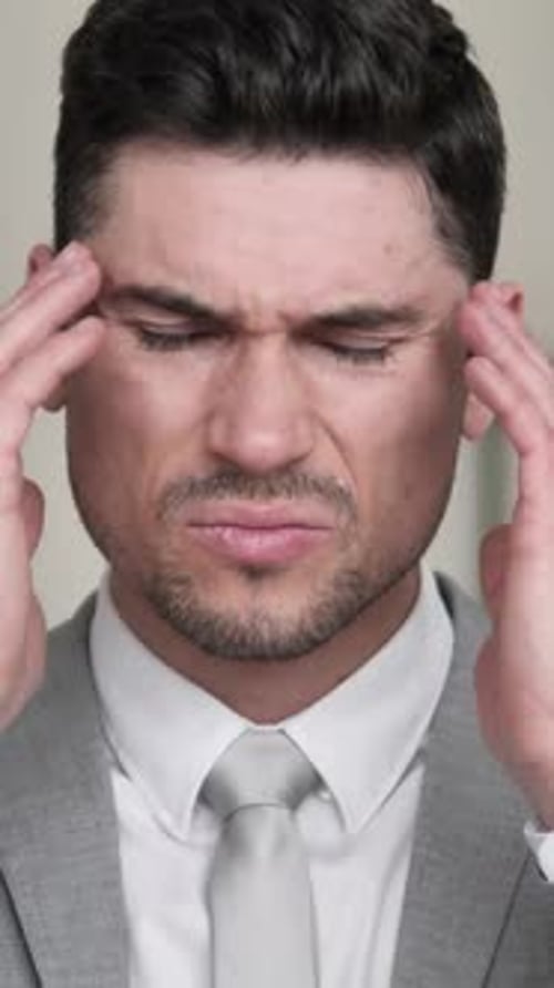 Man in Suit Rubbing Temples with a Headache