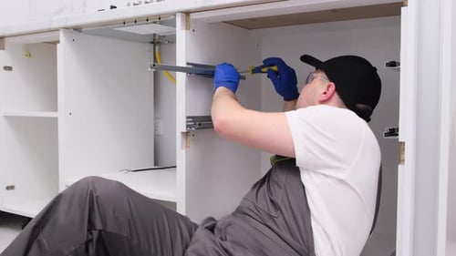 Tradesman Installing Drawer Tracks Under a White Counter