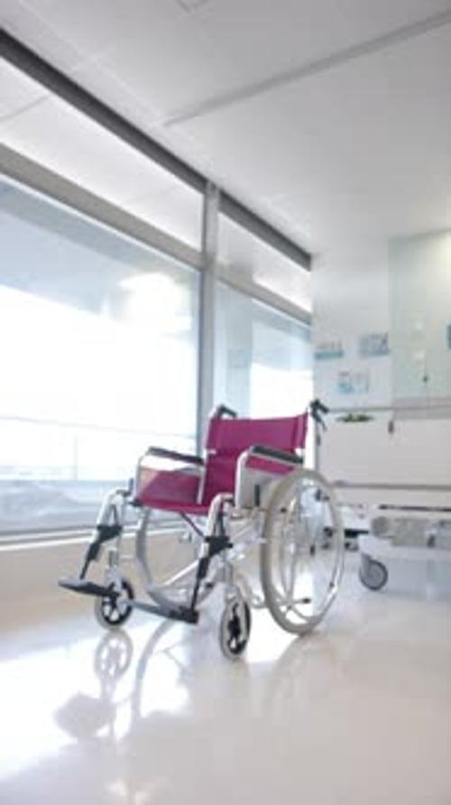 Vertical video of empty wheelchair and patient bed in the hospital ward