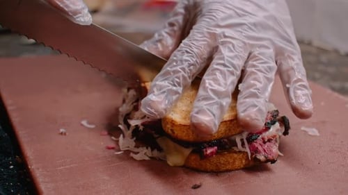 Chef Cutting Loaded Sandwich With Meat and Cheese