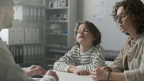 Young Boy and His Mother Talking to Doctor in Medical Office