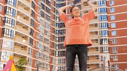Young Woman Stretching Outside Tall Apartment Building