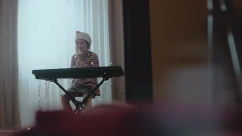 Child Plays Piano with Santa Hat at Home